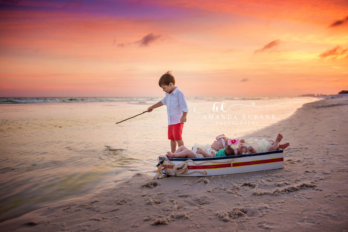 Seaside family photographer captures big brother fishing while baby sister sleeps in boat
