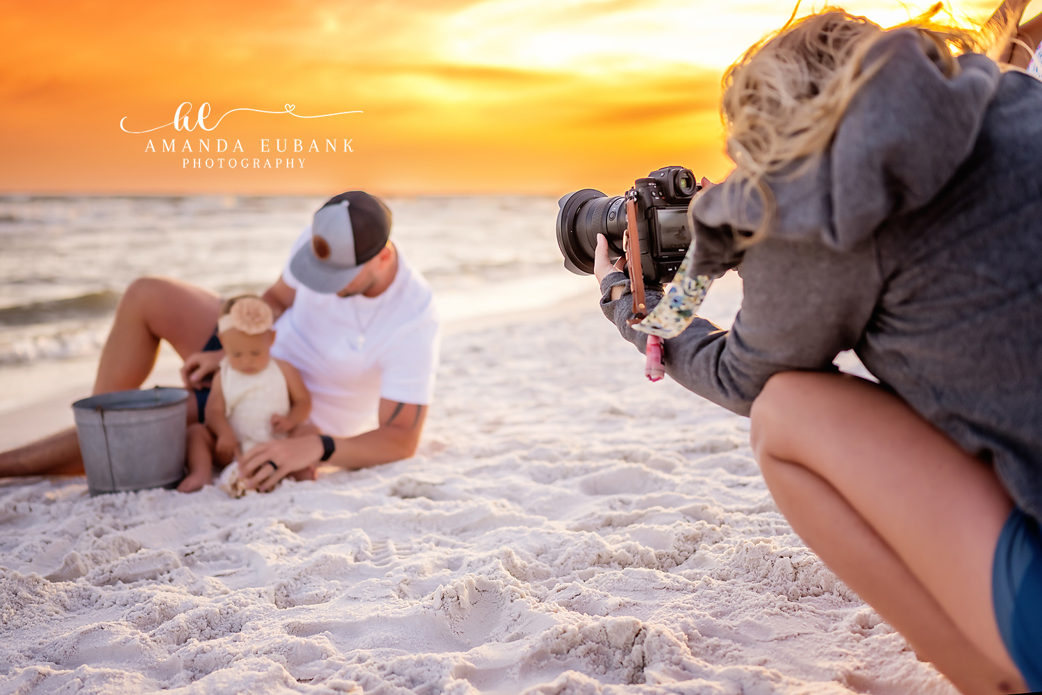 Seaside family photographer behind the scenes capturing dad and baby on beach at sunset