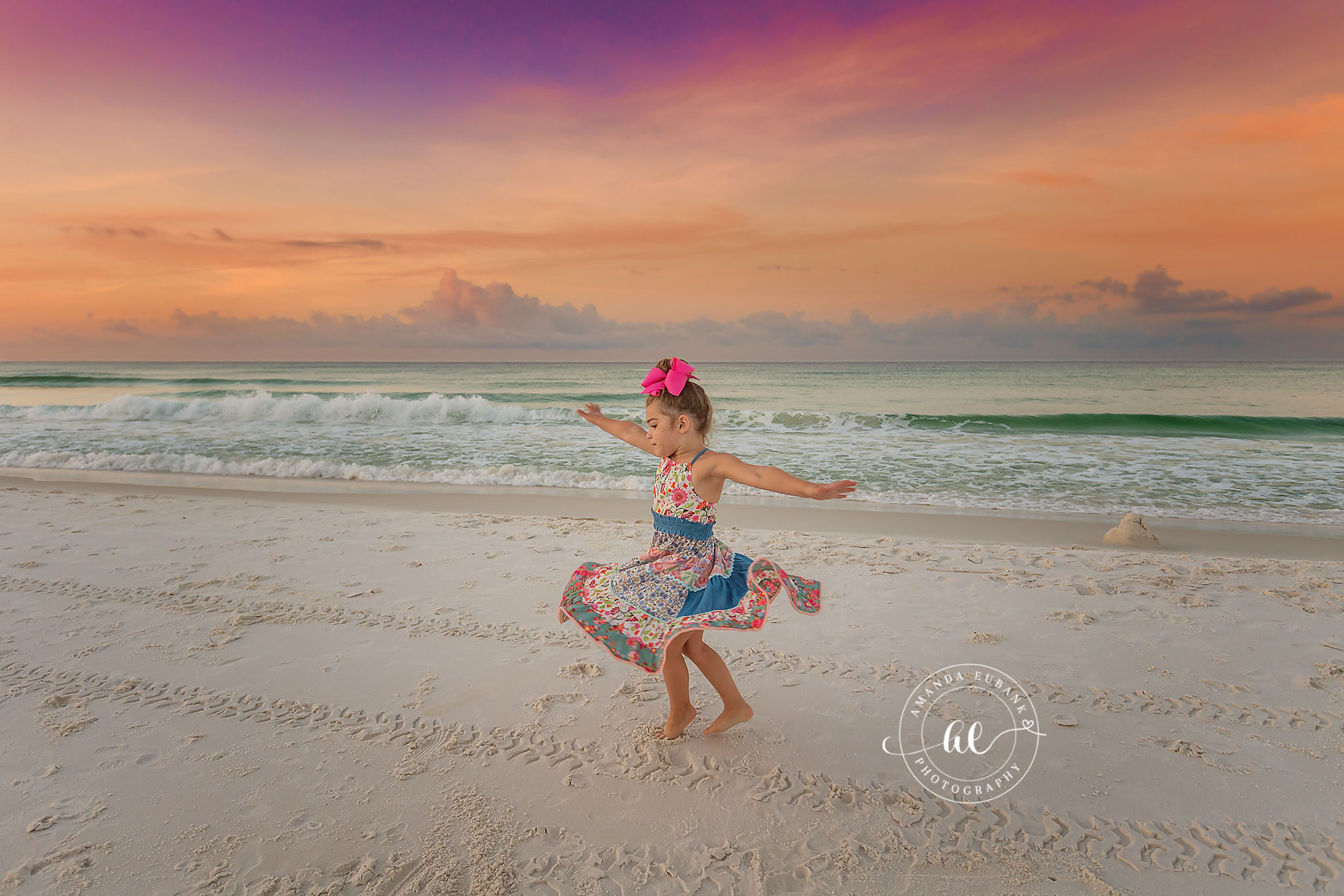 Seaside sunrise photographer captures little girl twirling on beach at vibrant sunrise